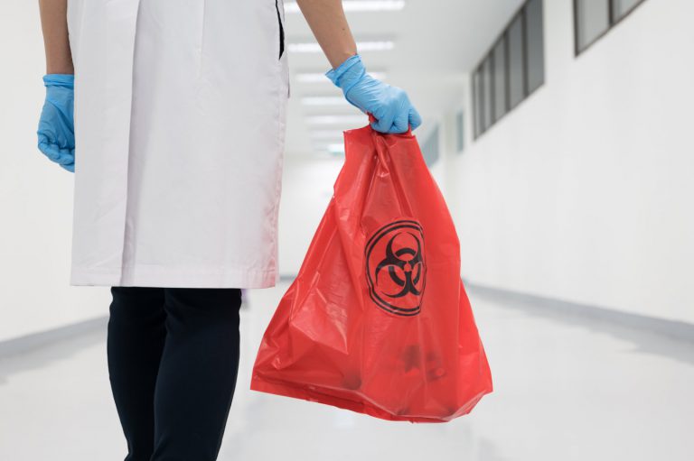 A doctor carrying a red medical waste bag